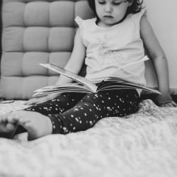 Preschooler concentrating whilst reading book lying in her nap