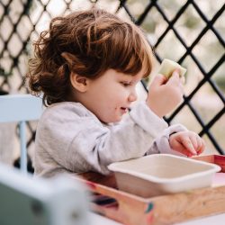 Two year old seated at table doing sponge painting