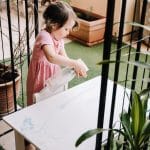 Three year old using spray to clean a table