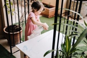 Three year old using spray to clean a table