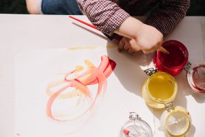 Toddler painting with red and yellow paints on white paper