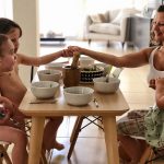 Two and three year olds sitting around a table saying Grace before mealtime